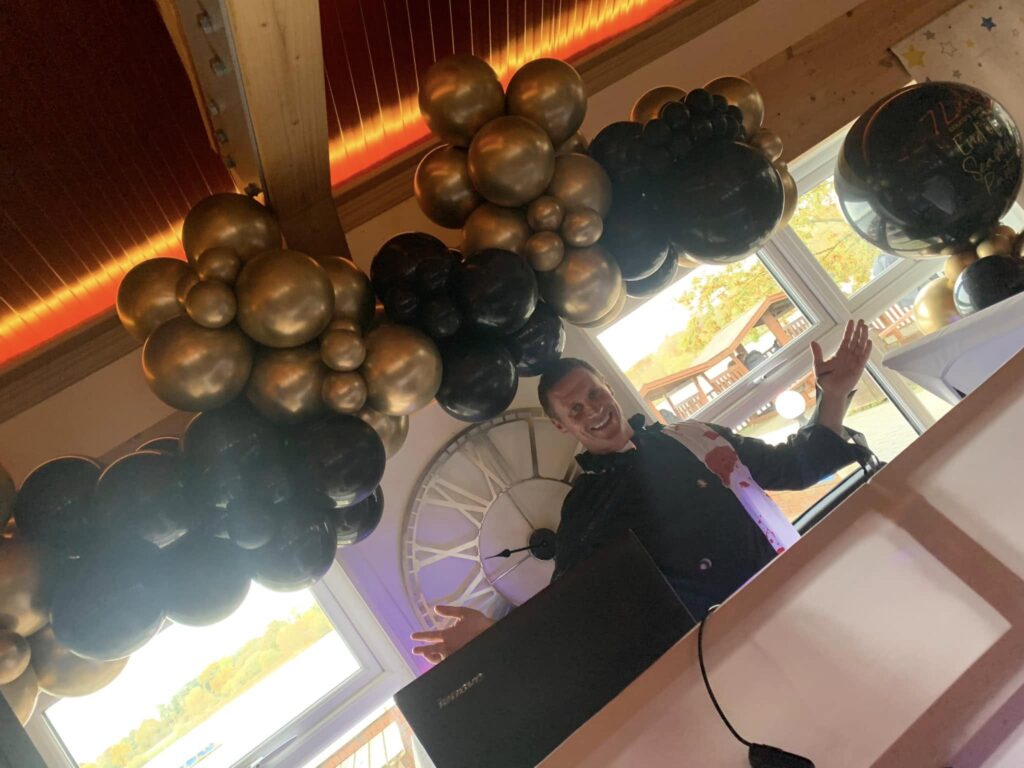 DJ Dan Endicott hosting a birthday party disco with gold balloon decor